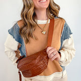 Woman holding a brown leather bag against a white background