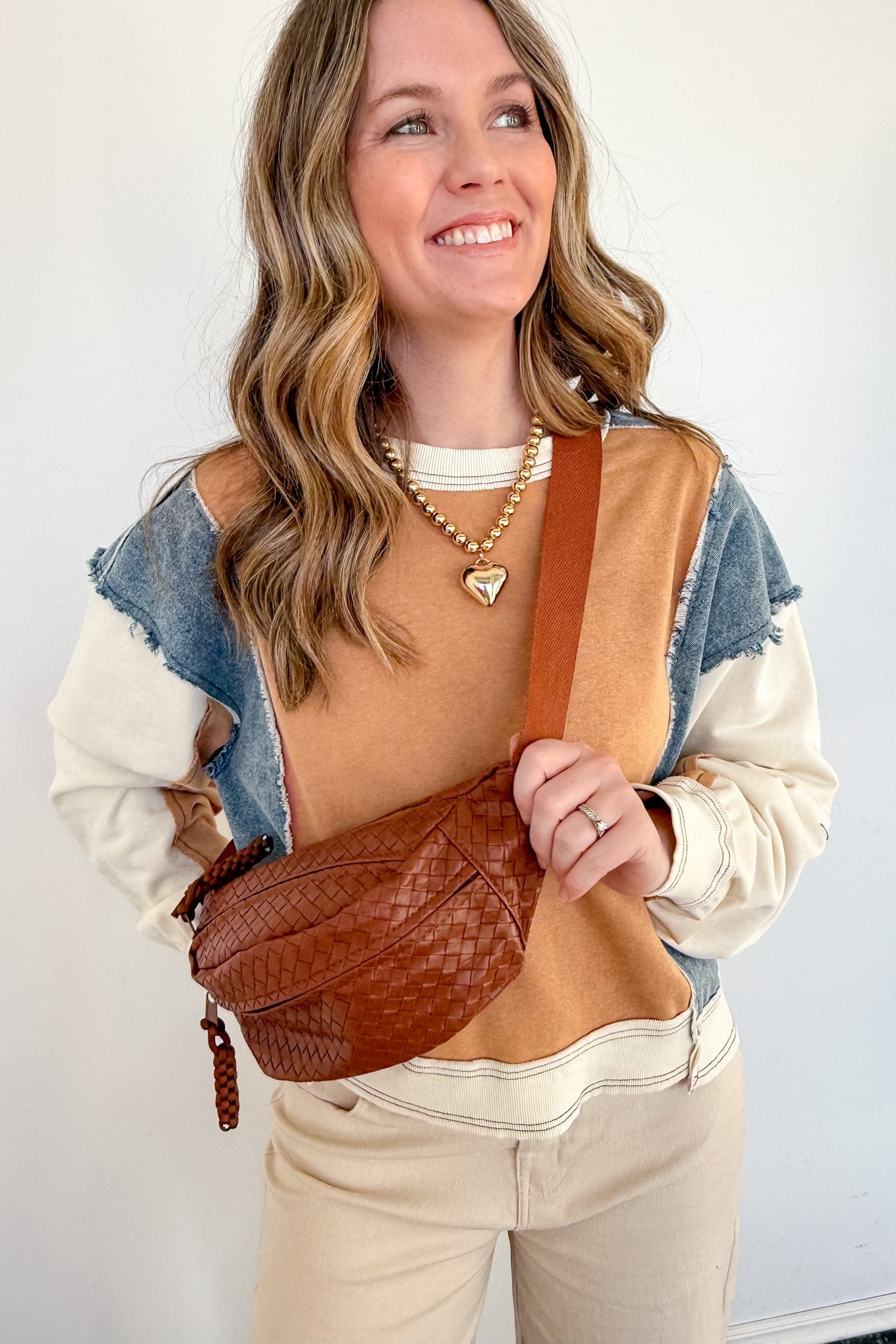 Woman holding a brown leather bag against a white background