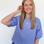Woman wearing a light blue top and jeans against a white background