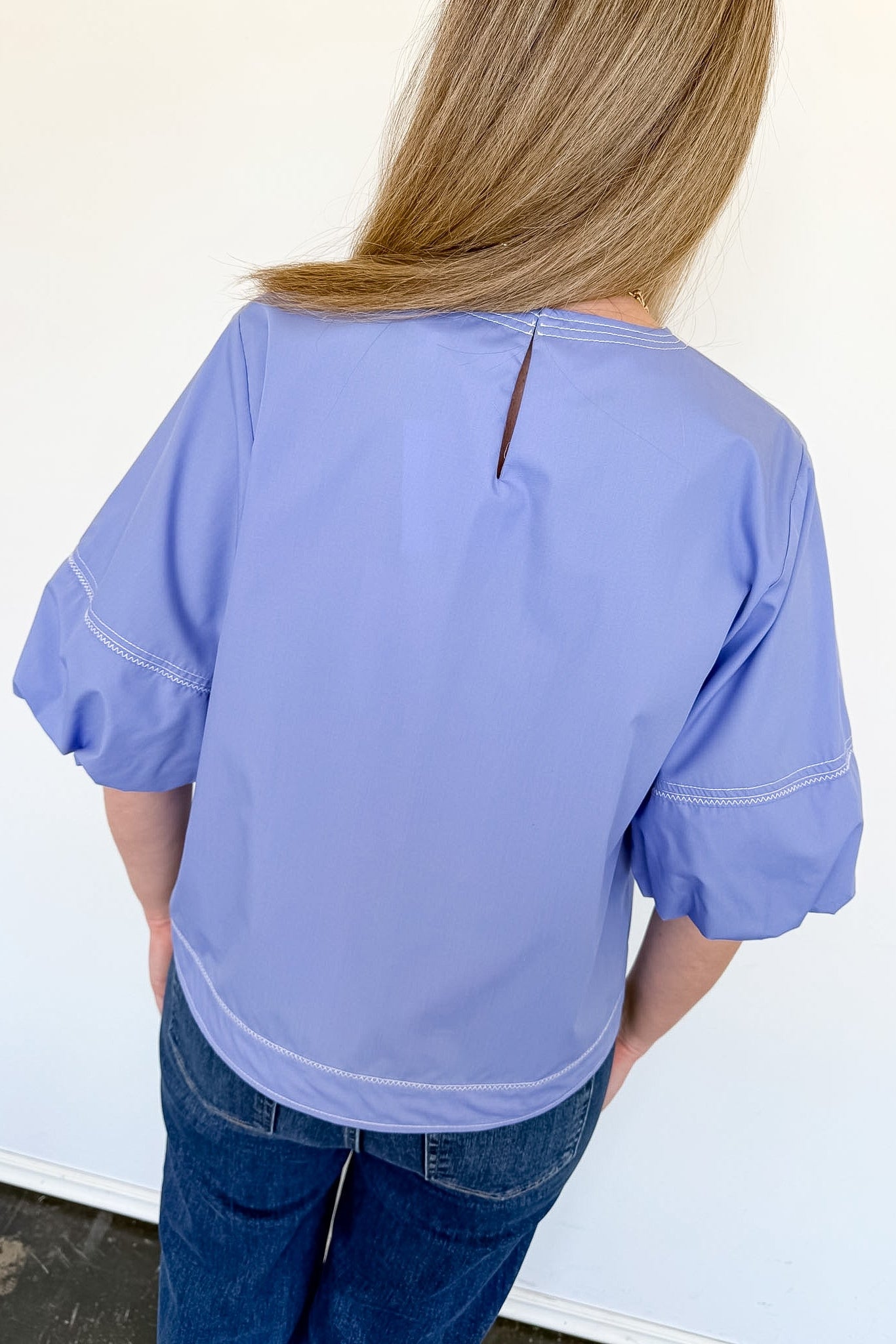 Person wearing a light blue blouse with a plain background