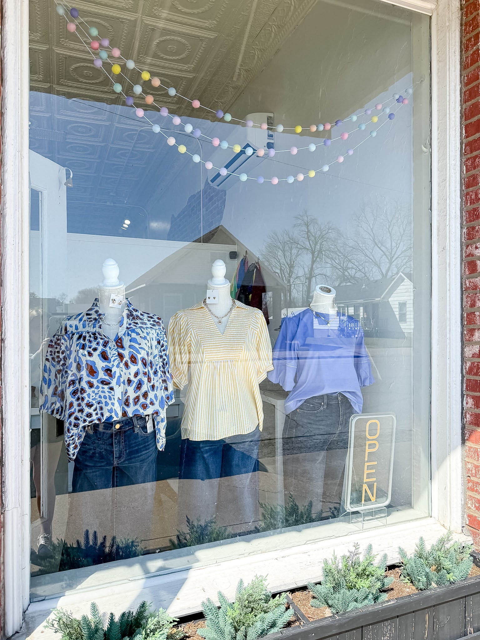 Mannequins in a store window display with clothing and a 'Zara' sign.