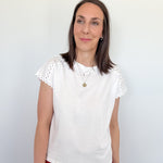 Woman wearing a white blouse with lace sleeves against a plain background