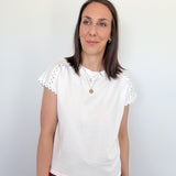 Woman wearing a white blouse with lace sleeves against a plain background