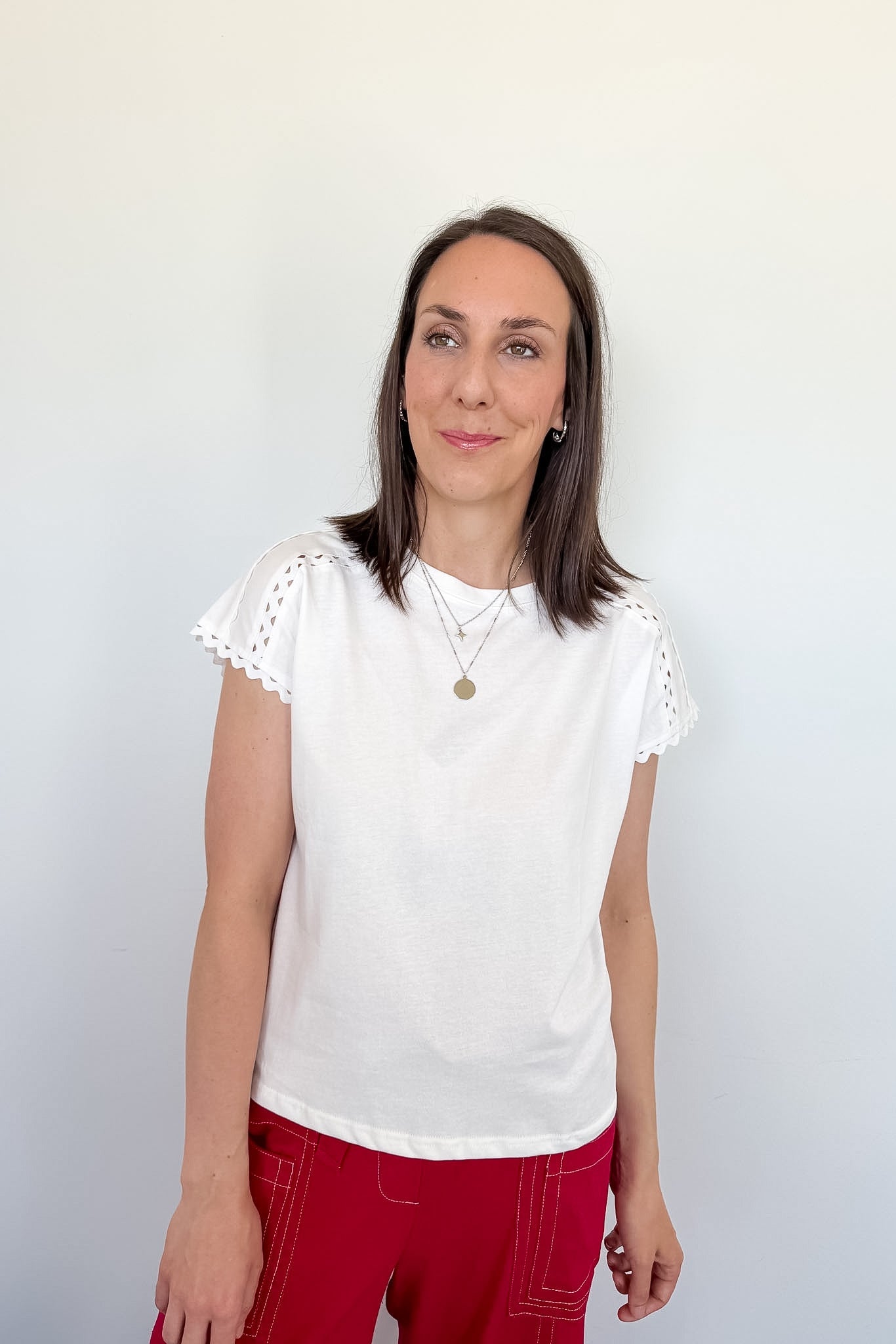 Woman wearing a white blouse with lace sleeves against a plain background