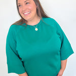 Woman wearing a green sweater against a white wall