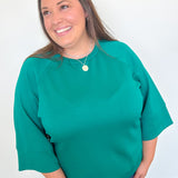 Woman wearing a green sweater against a white wall