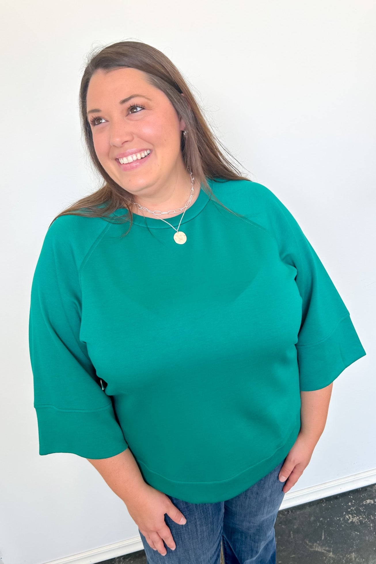 Woman wearing a green sweater against a white wall