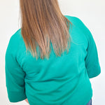 Person wearing a teal shirt and blue jeans from behind on a white background