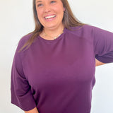 Woman wearing a purple sweater against a white background
