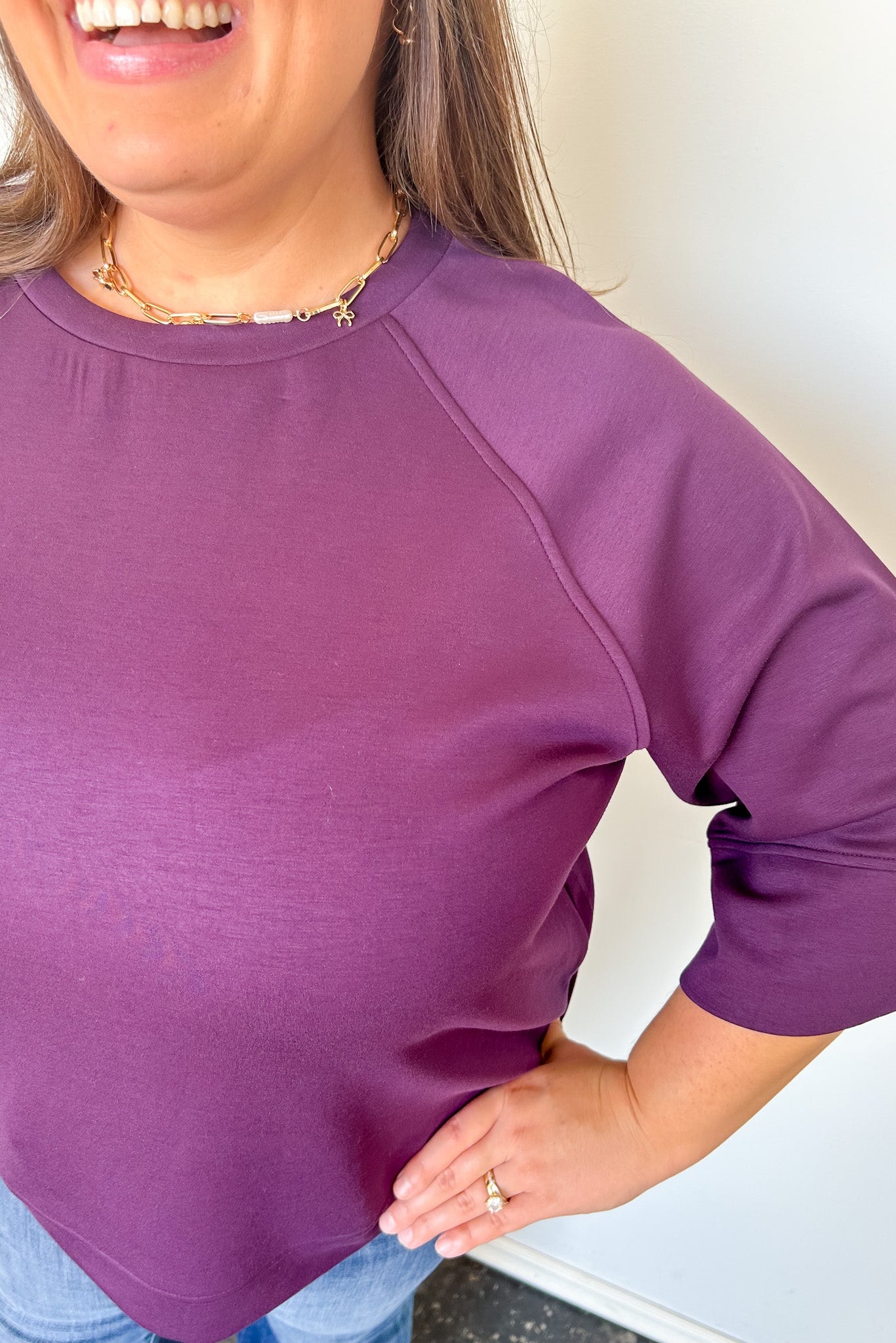 Person wearing a purple long-sleeve shirt with a plain background