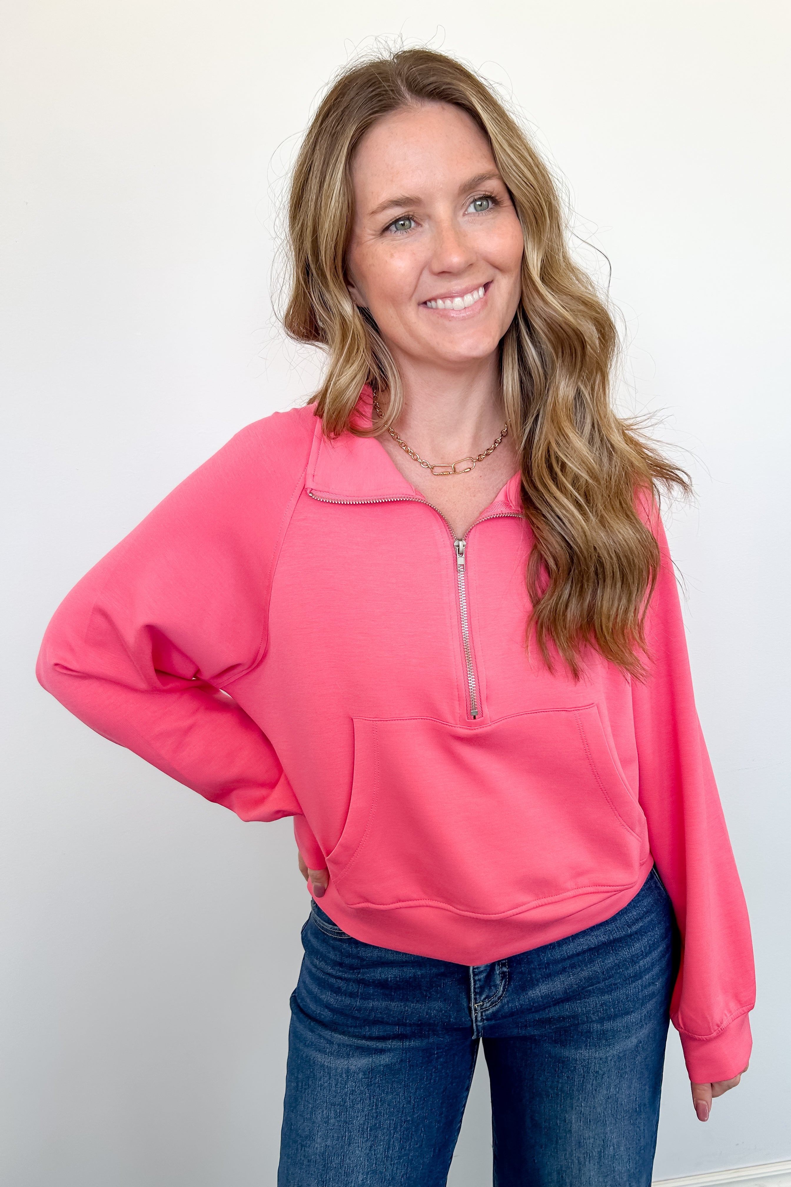 Woman wearing a pink pullover with a zipper on a white background