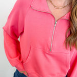 Person wearing a pink pullover with a zipper against a white background