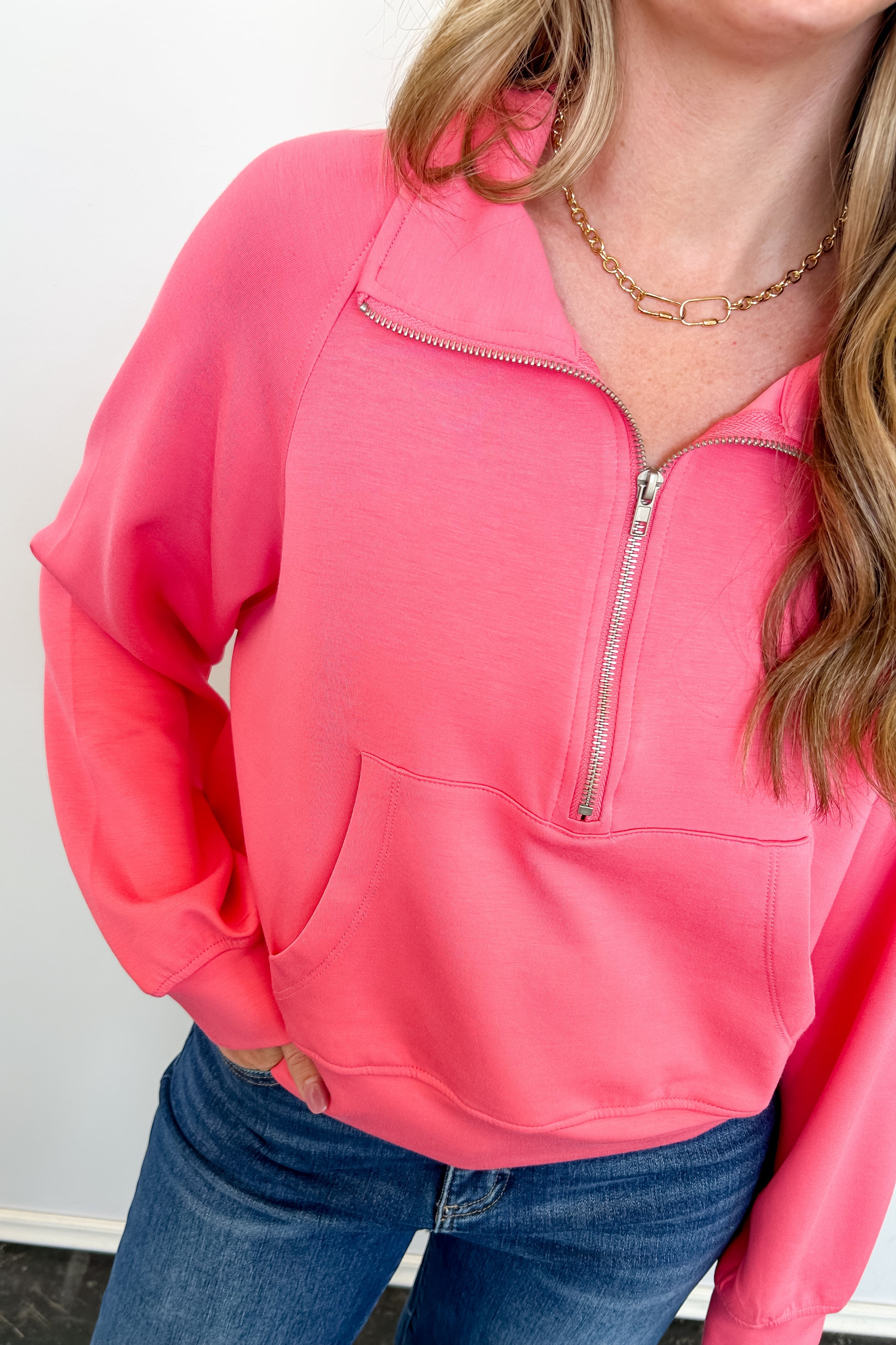 Person wearing a pink pullover with a zipper against a white background
