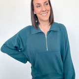Woman wearing a teal pullover with a zipper on a white background