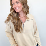 Woman wearing a beige long-sleeve shirt with a quarter zip on a white background