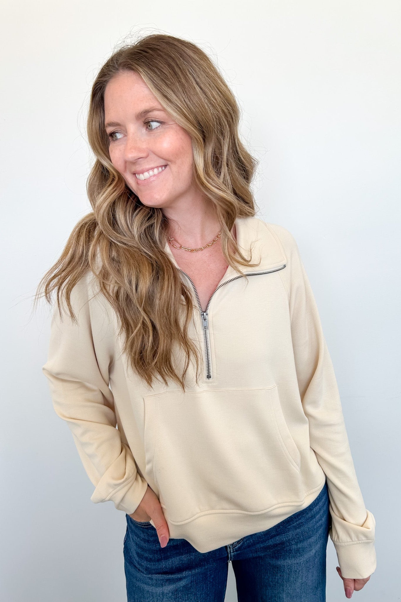 Woman wearing a beige long-sleeve shirt with a quarter zip on a white background