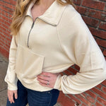 Woman wearing a beige sweatshirt with jeans.