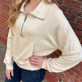 Woman wearing a beige sweatshirt with jeans.