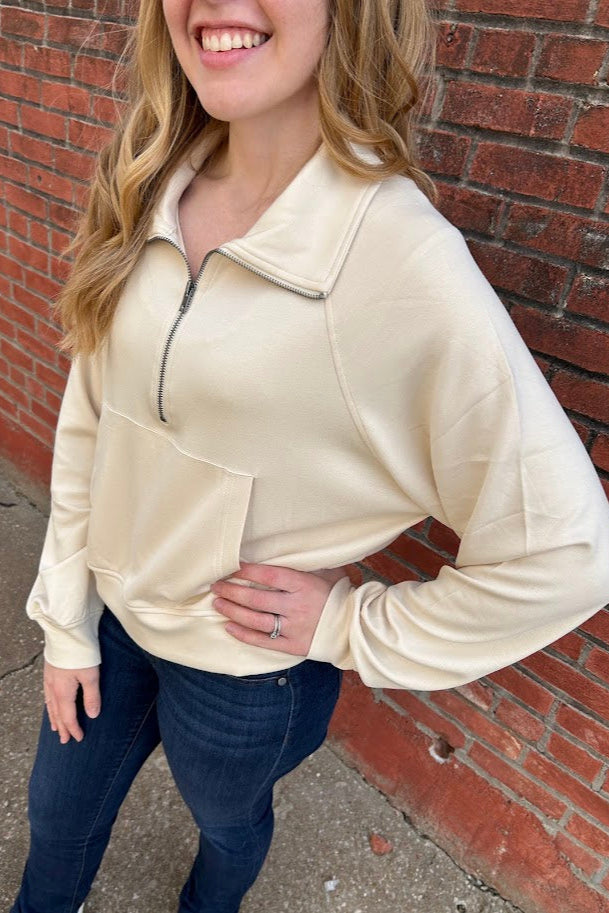 Woman wearing a beige sweatshirt with jeans.