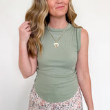Woman wearing a green sleeveless top and floral pants against a white background