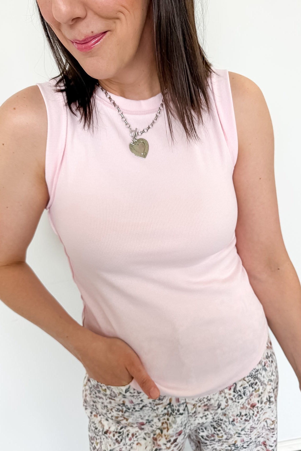 Person wearing a light pink sleeveless top and patterned leggings against a white background