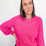 Woman wearing a bright pink cardigan against a white background
