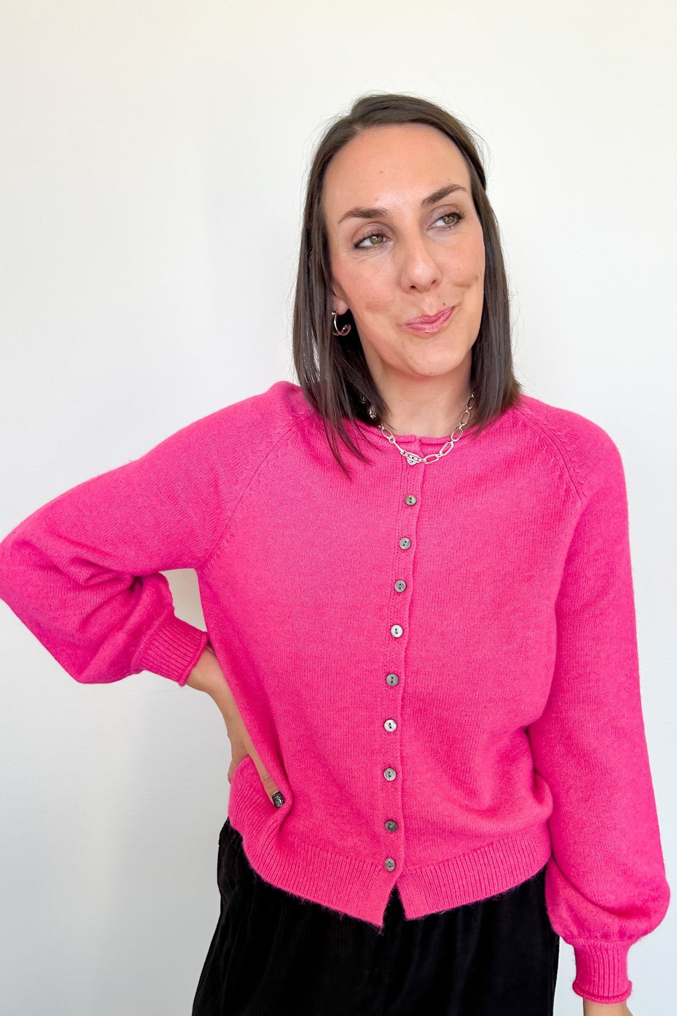 Woman wearing a bright pink cardigan against a white background