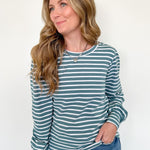 Woman wearing a striped long-sleeve shirt and jeans against a white background