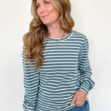 Woman wearing a striped long-sleeve shirt and jeans against a white background