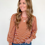 Woman wearing a striped orange and white long-sleeve shirt against a white background