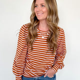 Woman wearing a striped orange and white long-sleeve shirt against a white background