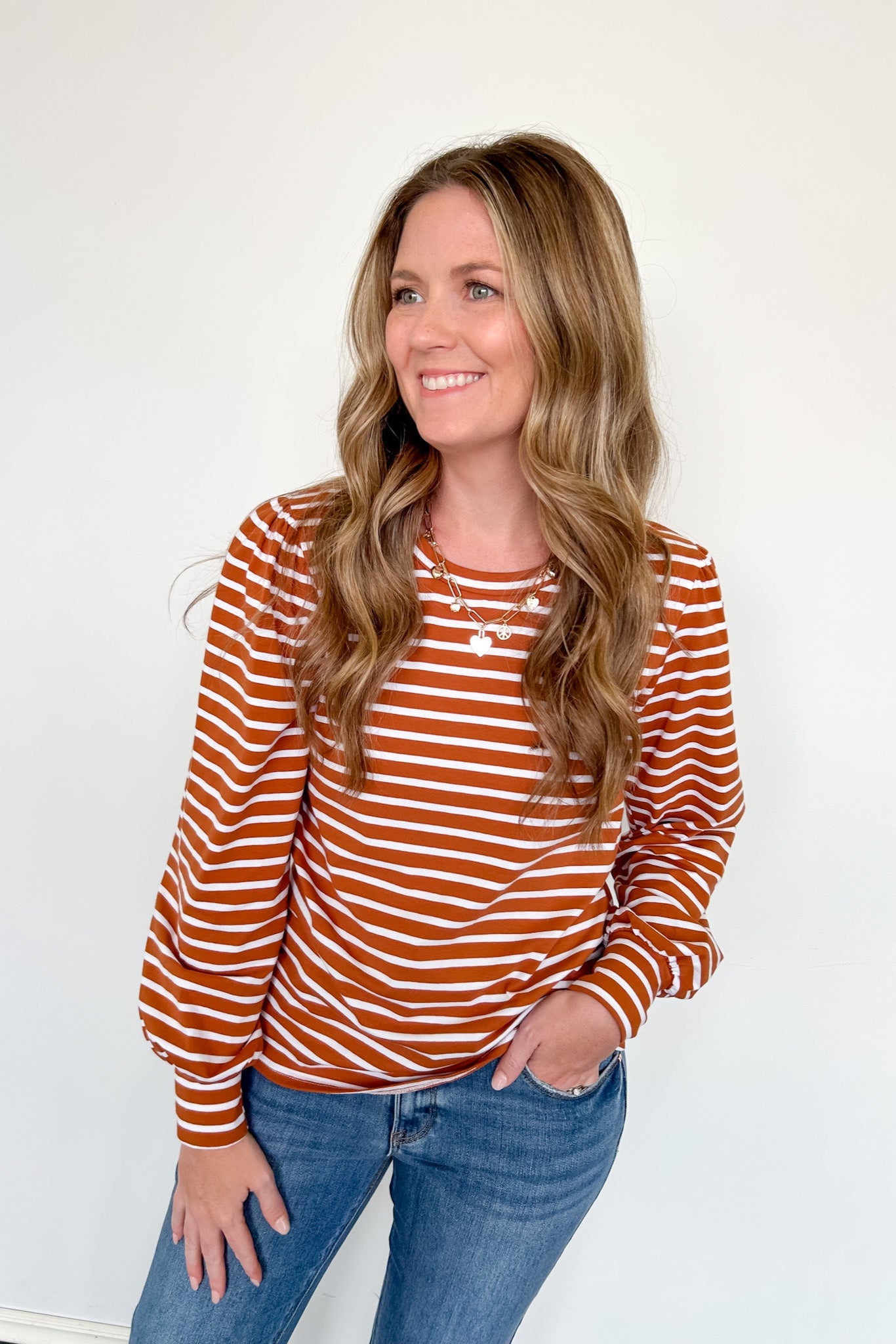 Woman wearing a striped orange and white long-sleeve shirt against a white background