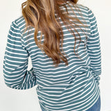 Person wearing a green and white striped long-sleeve shirt with blue jeans against a white background