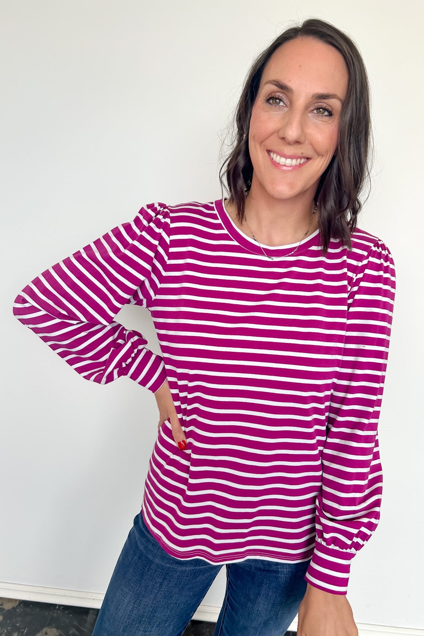 Woman wearing a pink and white striped long-sleeve shirt against a white background