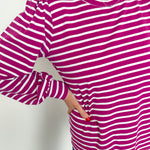 Person wearing a purple and white striped long-sleeve shirt against a plain background