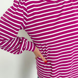 Person wearing a purple and white striped long-sleeve shirt against a plain background