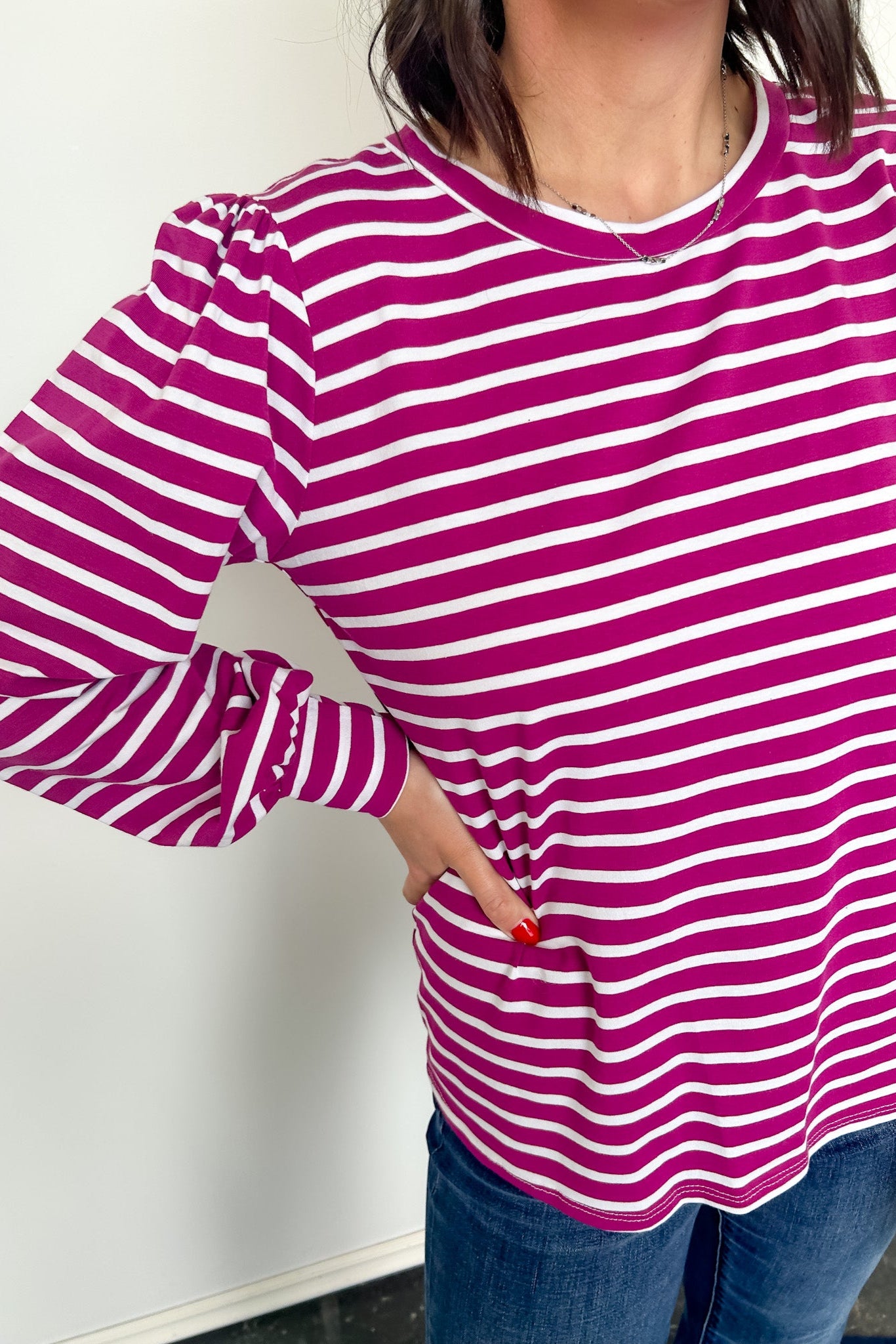 Person wearing a purple and white striped long-sleeve shirt against a plain background