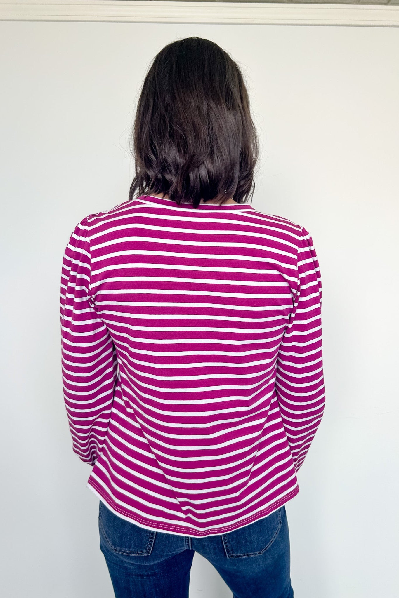 Person wearing a pink and white striped shirt against a white background