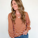 Woman wearing a striped long-sleeve top and jeans on a white background