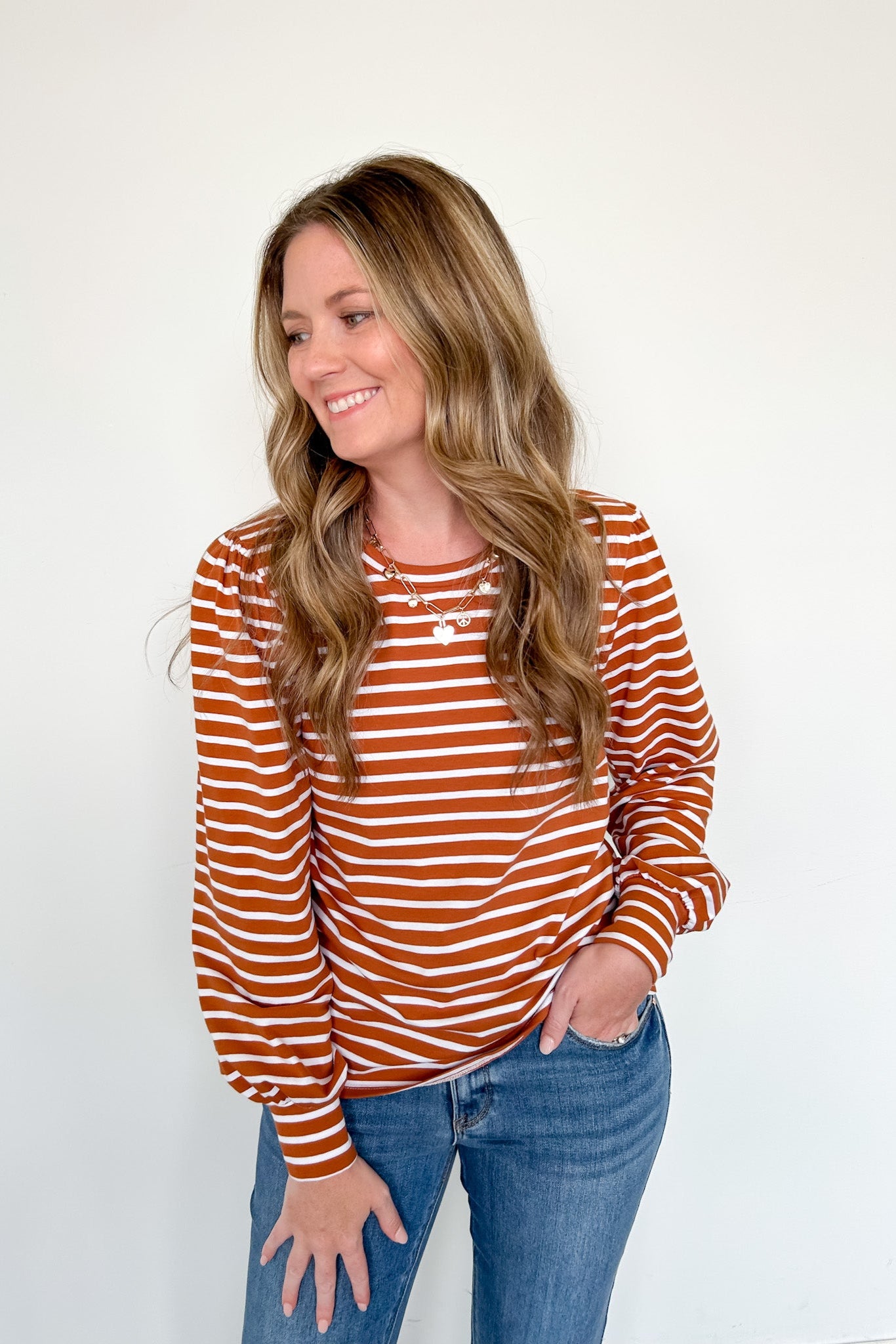 Woman wearing a striped long-sleeve top and jeans on a white background