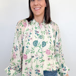 Woman wearing a floral blouse and jeans against a white background