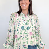 Woman wearing a floral blouse and jeans against a white background