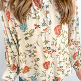 Person wearing a floral blouse with a plain background