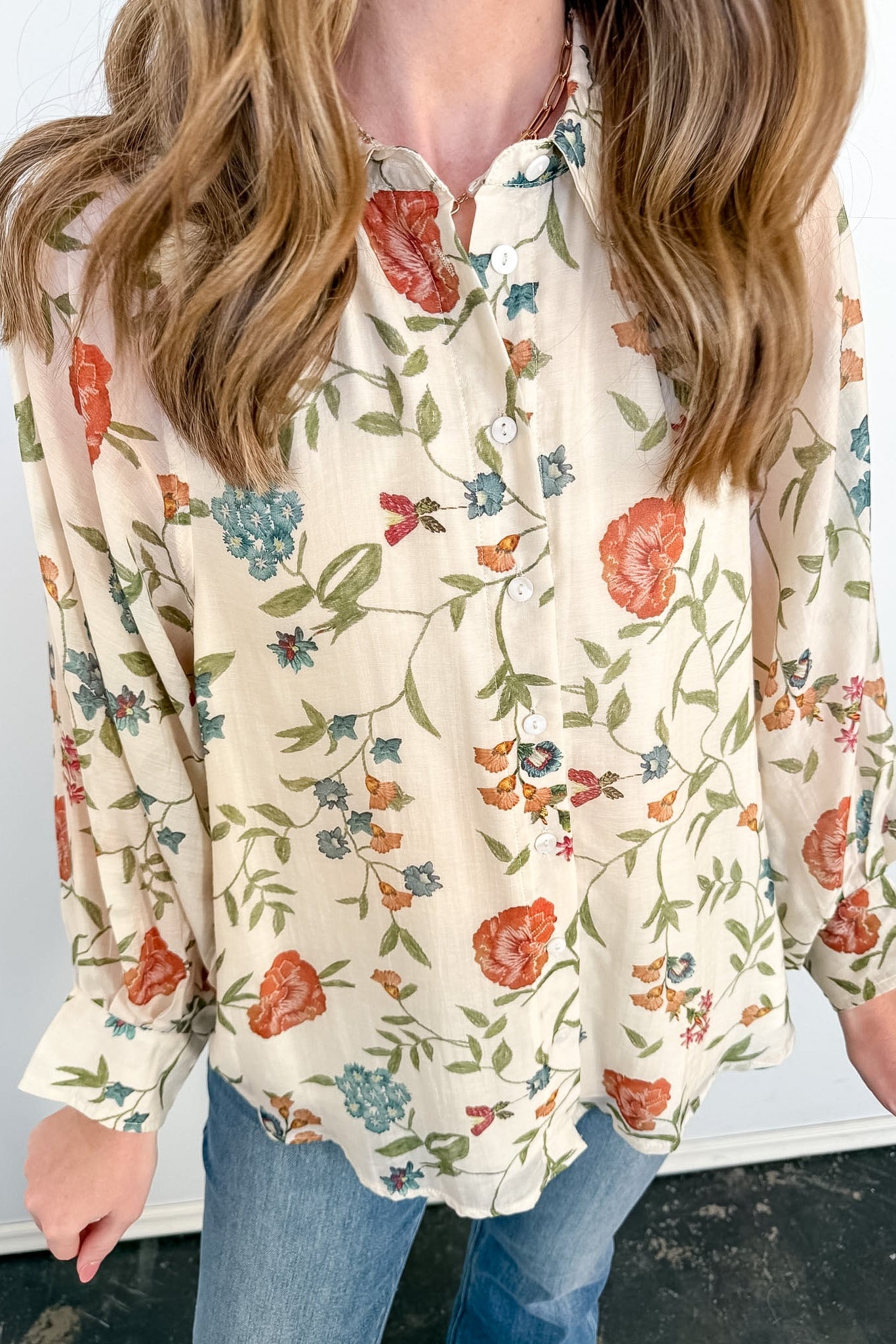 Person wearing a floral blouse with a plain background