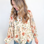 Woman wearing a floral blouse and jeans against a white background