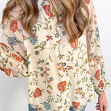 Woman wearing a floral blouse with long sleeves against a white background