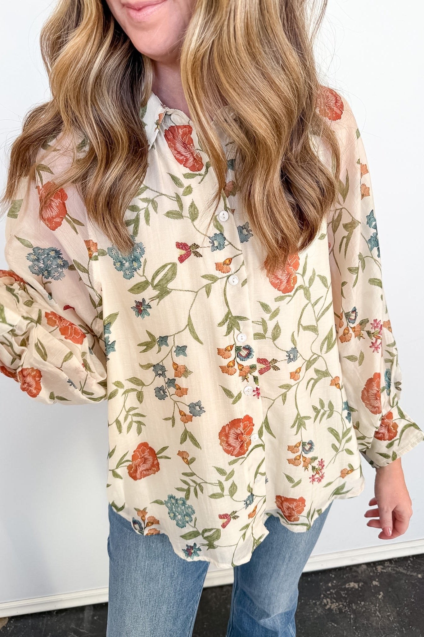 Woman wearing a floral blouse with long sleeves against a white background