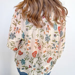 Person wearing a floral blouse with a plain background