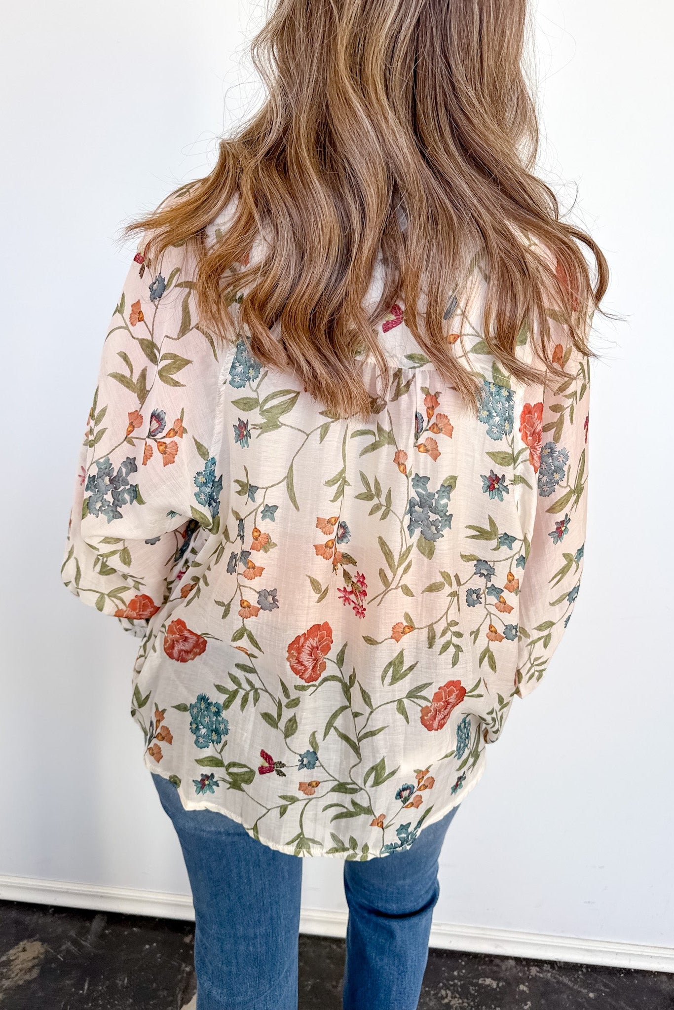 Person wearing a floral blouse with a plain background