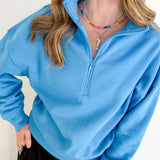 Person wearing a blue pullover with a zipper against a white background